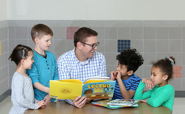 Students from Terry Redlin Elementary read a book with Principal Ryan DeGraff